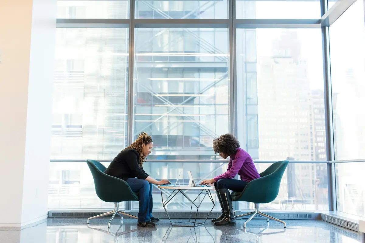 Two colleagues in a check-in conversation by a window