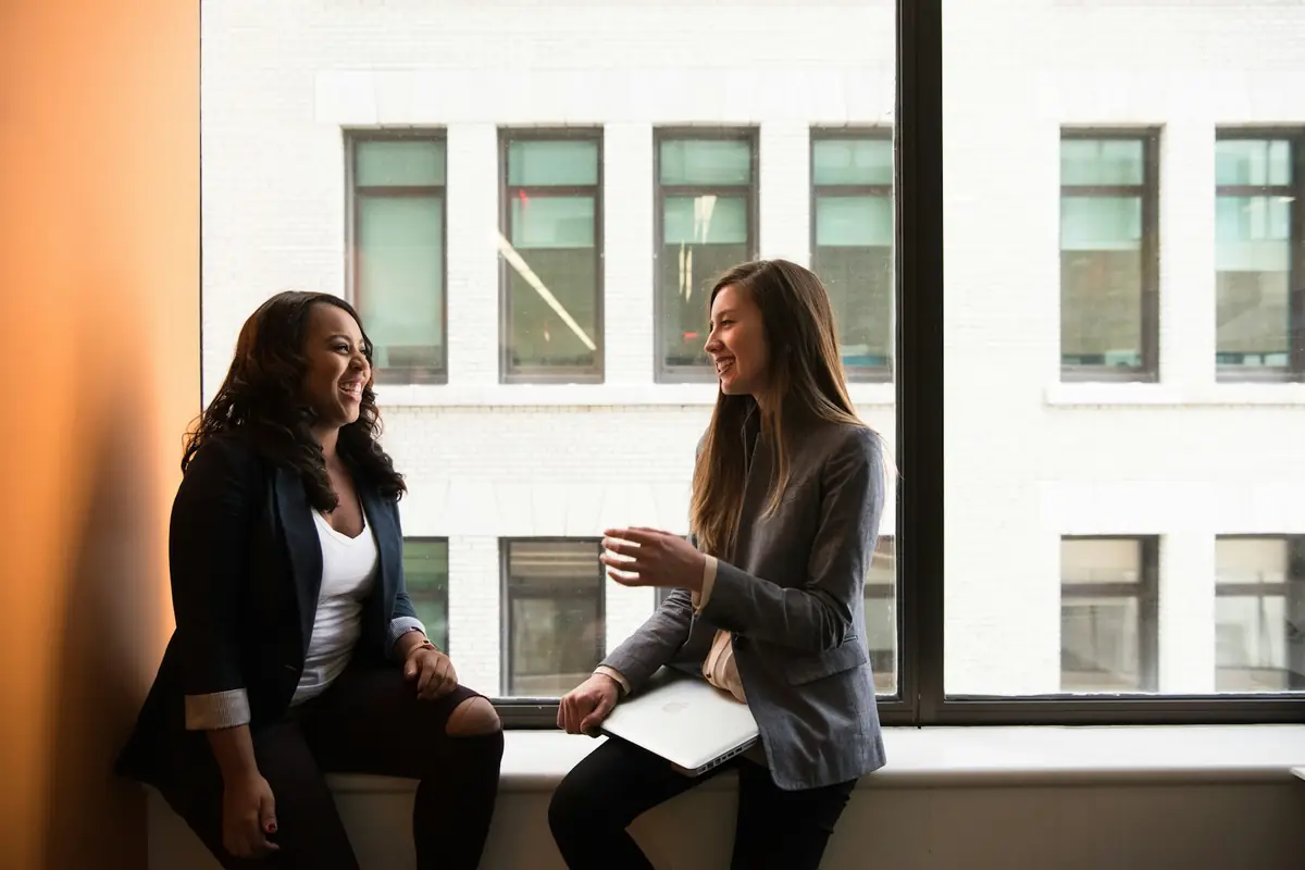 Two colleagues discussing terms by an office window